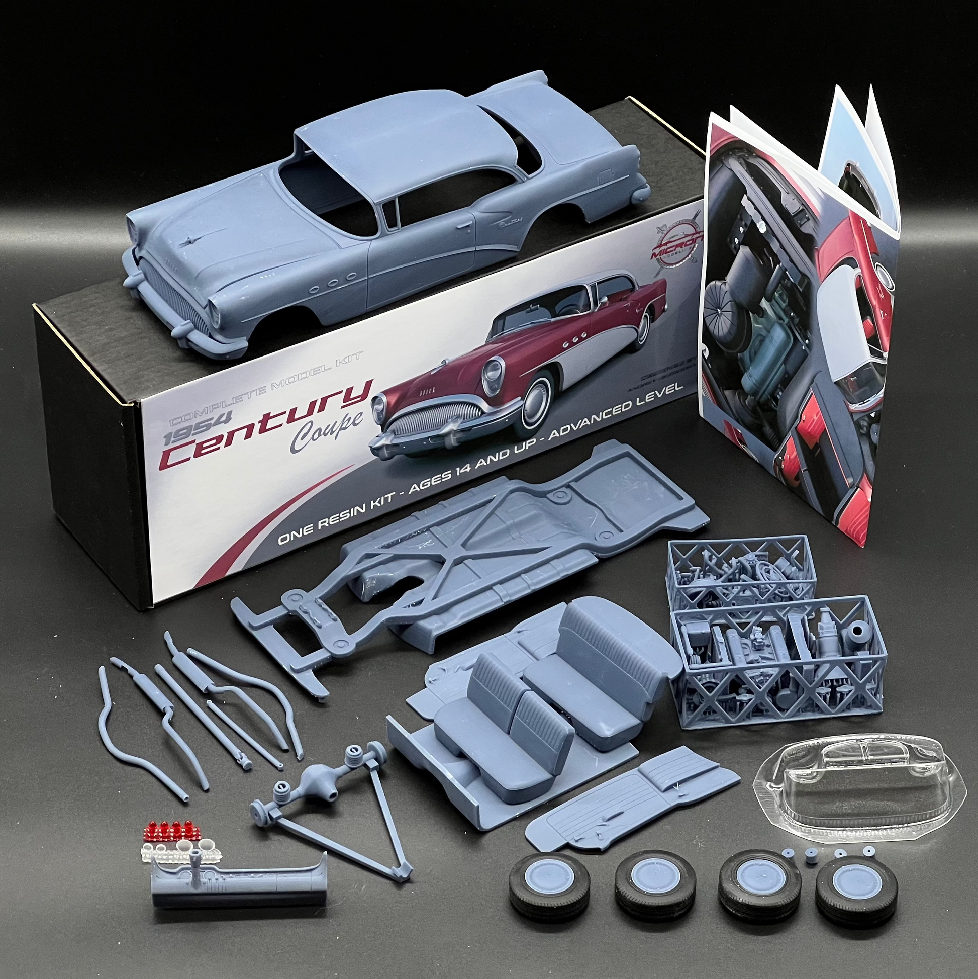 A 1954 Buick Century Coupe model car kit laid out on a dark surface, including a light blue unpainted classic car body, printed packaging, instruction sheets, small parts, wheels, and a clear hood piece. The box reads 'Century Coupe' and shows a red-and-white car illustration.